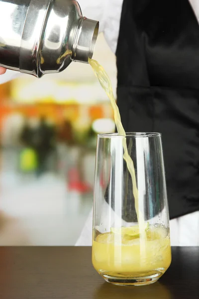 Barmen hand with shaker pouring cocktail into glass, on bright background — Stock Photo, Image