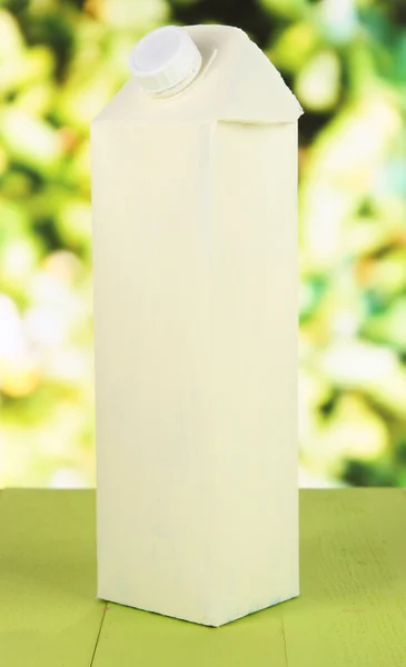 Milchpackung auf Tisch vor hellem Hintergrund — Stockfoto