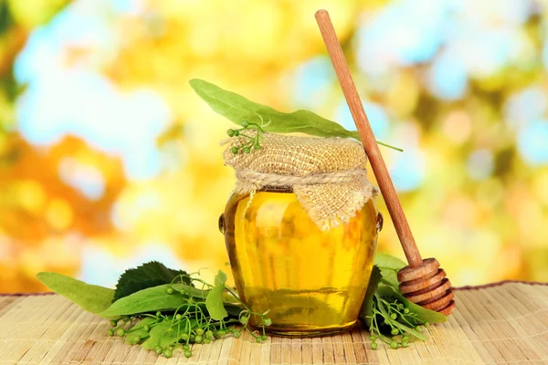 Glas Honig mit Blüten aus Kalk, auf farbiger Bambusmatte auf hellem Hintergrund — Stockfoto