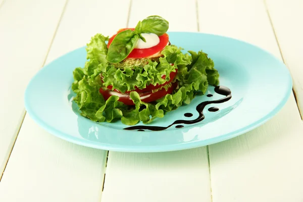 Smakelijke geroosterde merg en tomaat segmenten met salade bladeren, op houten achtergrond — Stockfoto