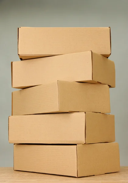 Cajas de paquetes sobre mesa de madera, sobre fondo gris —  Fotos de Stock