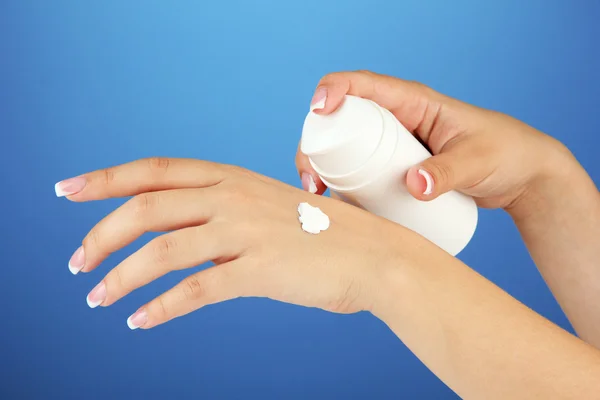 Woman applying cream on hands on color background — Stock Photo, Image