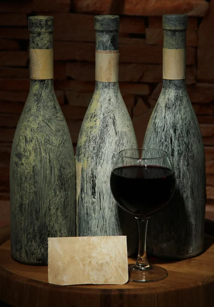 Composition avec vieille bouteille de vin et verre à vin dans une ancienne cave, sur fond sombre — Photo