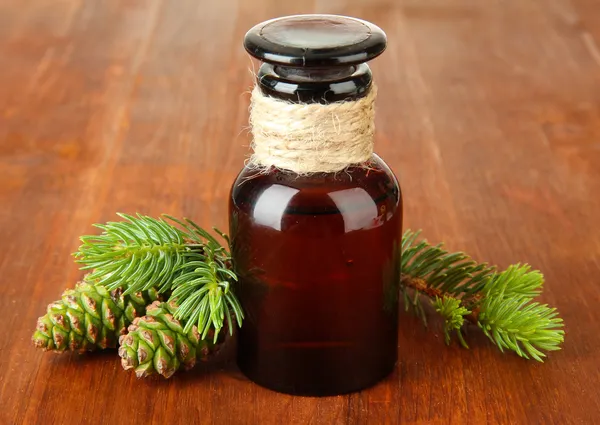 Botella de aceite de abeto y conos verdes sobre fondo de madera — Foto de Stock