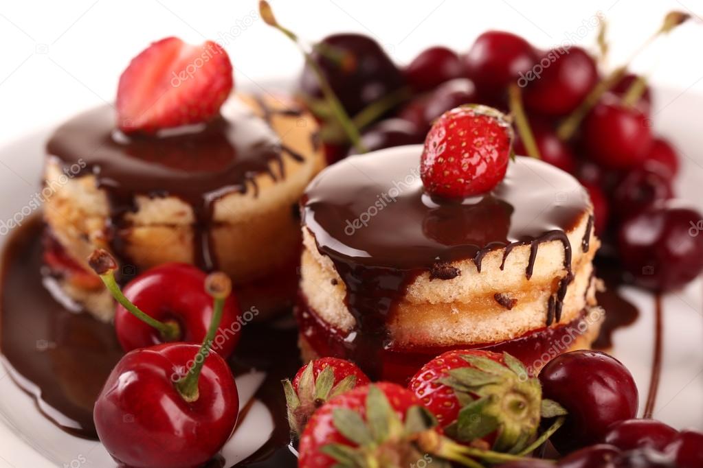Tasty biscuit cakes with chocolate and berries on plate, close up
