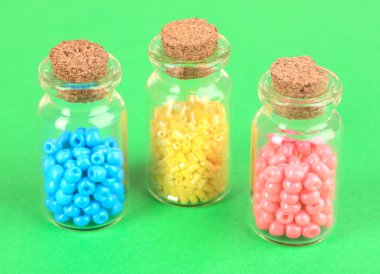 yeşil zemin üzerine şişelerde farklı renkli boncuklar