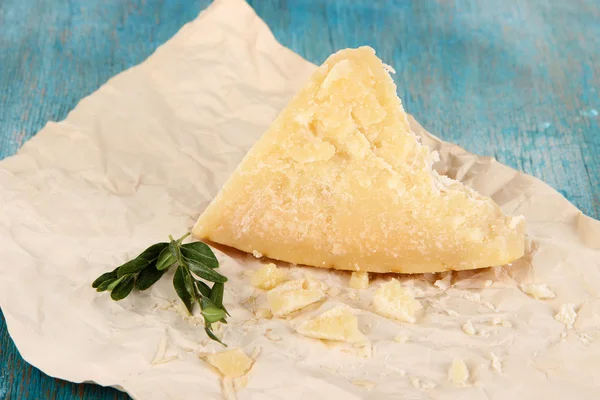 Pedaço de queijo parmesão em papel sobre mesa de madeira close-up — Fotografia de Stock