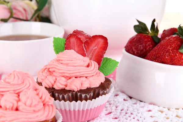 Beautiful strawberry cupcakes and flavored tea on dining table close-up — Stock Photo, Image
