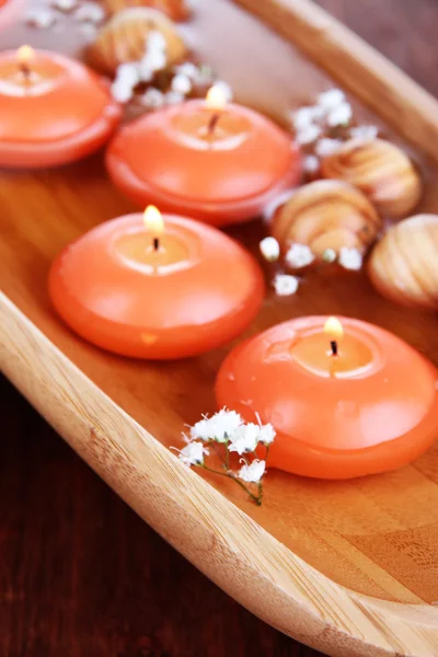 Beautiful candles in water on wooden table close-up — Stock Photo, Image