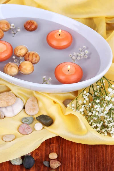 Beautiful candles swim in beautiful plate on yellow fabric close-up — Stock Photo, Image