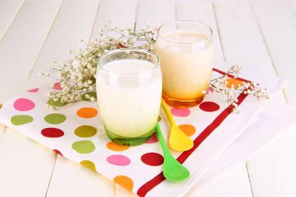 Вкусные йогурты с фруктами в стаканах на деревянном столе крупным планом — стоковое фото