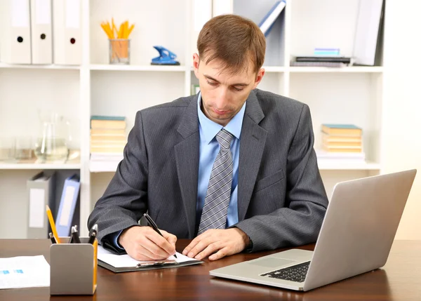 Jonge zakenman in kantoor op zijn werkplek — Stockfoto