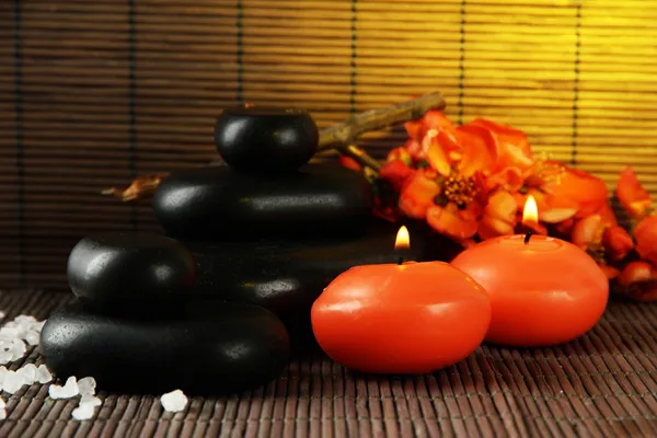 Piedras de spa con flores y velas sobre fondo de bambú — Foto de Stock