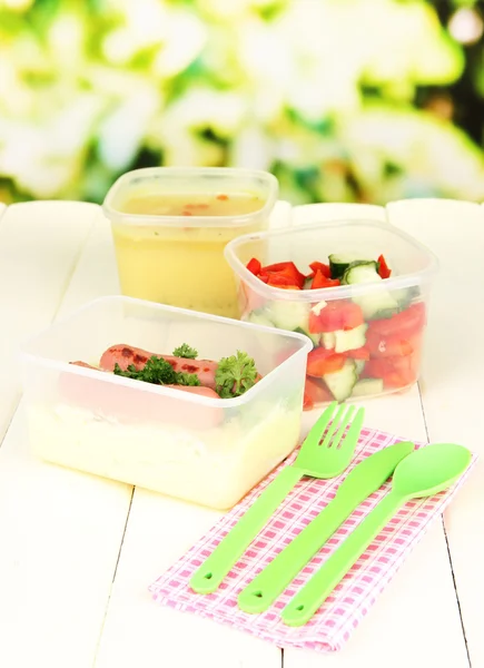 Gustoso pranzo in contenitori di plastica, su tavolo di legno su sfondo luminoso — Foto Stock