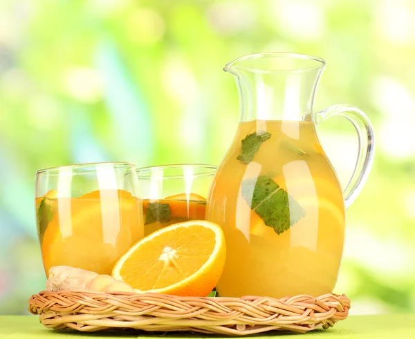 Pomerančová limonáda v džbán a sklenice na dřevěný stůl na přírodní pozadí — Stock fotografie