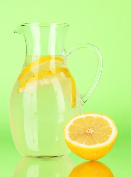 Lemonade in pitcher on green background — Stock Photo, Image