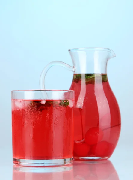 Kirschgetränk in Krug und Glas auf blauem Hintergrund — Stockfoto