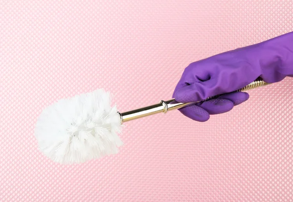 Toilet brush in hand on pink background — Stock Photo, Image