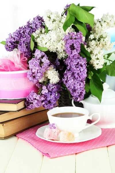 Σύνθεση με όμορφα ιώδη λουλούδια, τσάι υπηρεσία σε ξύλινο τραπέζι σε φωτεινό φόντο — Φωτογραφία Αρχείου