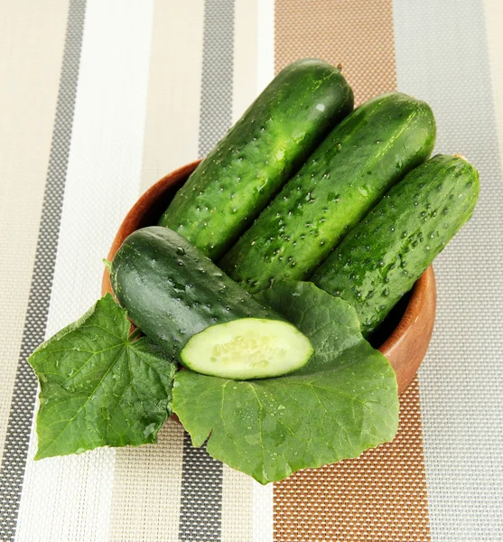 Tasty green cucumbers in wooden bowl, on bright background — Stock Photo, Image