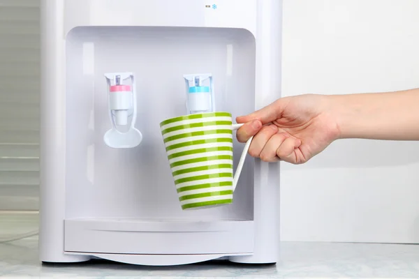 Woman filling cup at water cooler — Stock Photo, Image