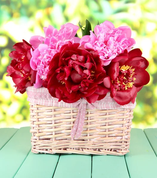 Beautiful peonies in wicker basket on table on bright background — Stock Photo, Image
