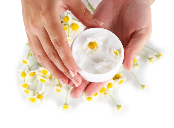 Cream with chamomile in hand isolated on white