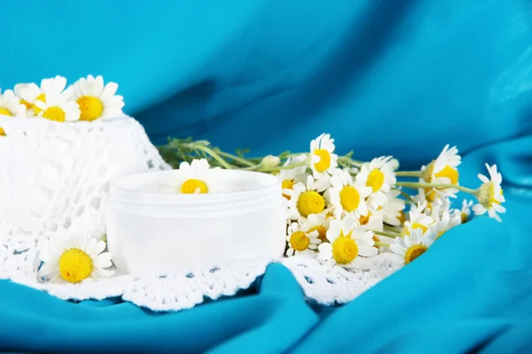 Creme com camomila em guardanapo em fundo de tecido azul — Fotografia de Stock