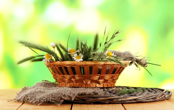 多小穗和洋甘菊上缎自然背景上的木桌上的篮子里 — 图库照片