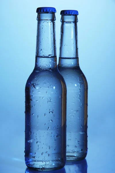 Vizes palackok kék háttér — Stock Fotó