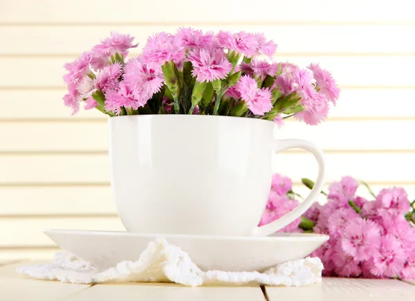 Muchos pequeños dientes de color rosa en taza sobre fondo de madera — Foto de Stock