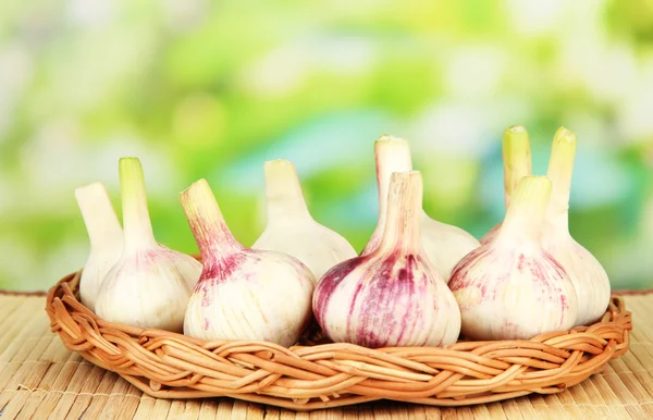Fresh garlic on wicker mat, on bright background — Stock Photo, Image