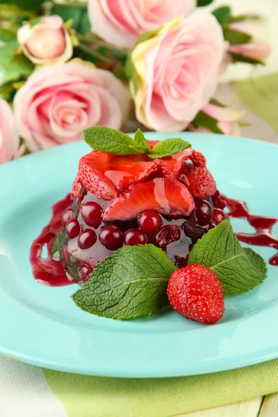 Tasty jelly dessert with fresh berries, on pink roses background — Stock Photo, Image