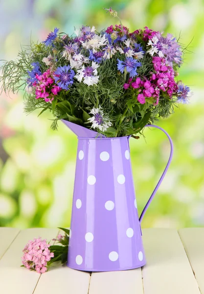 Beautiful bouquet in pitcher on wooden table on natural background — Stock Photo, Image
