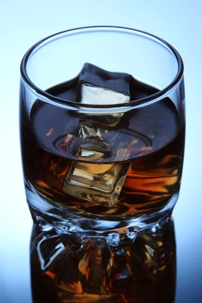 Brandy glass with ice on blue background — Stockfoto