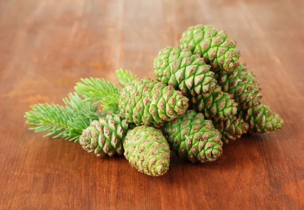 Green cones and fir tree on wooden background — Stock Photo, Image