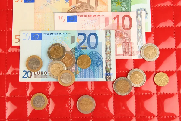 Euro banknotes and euro cents on red background — Stock Photo, Image