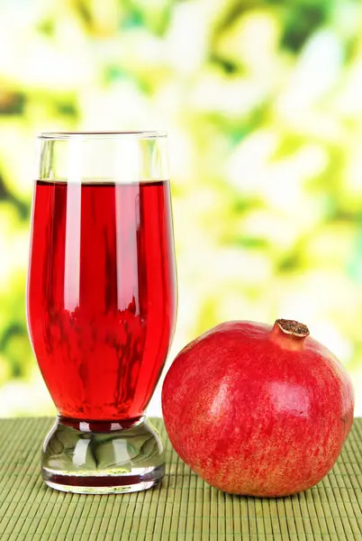 Glass of fresh garnet juice on table on bright background — Stock Photo, Image