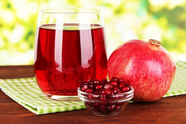 Vaso de jugo de granate fresco en la mesa sobre fondo brillante — Foto de Stock