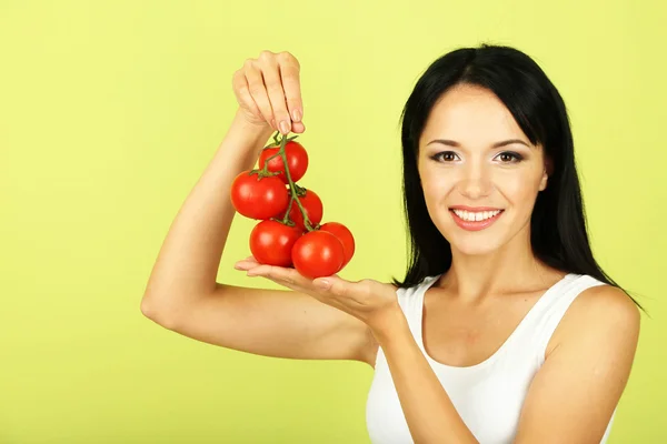 Girl with fresh tomatoes on green background — Stock Photo, Image