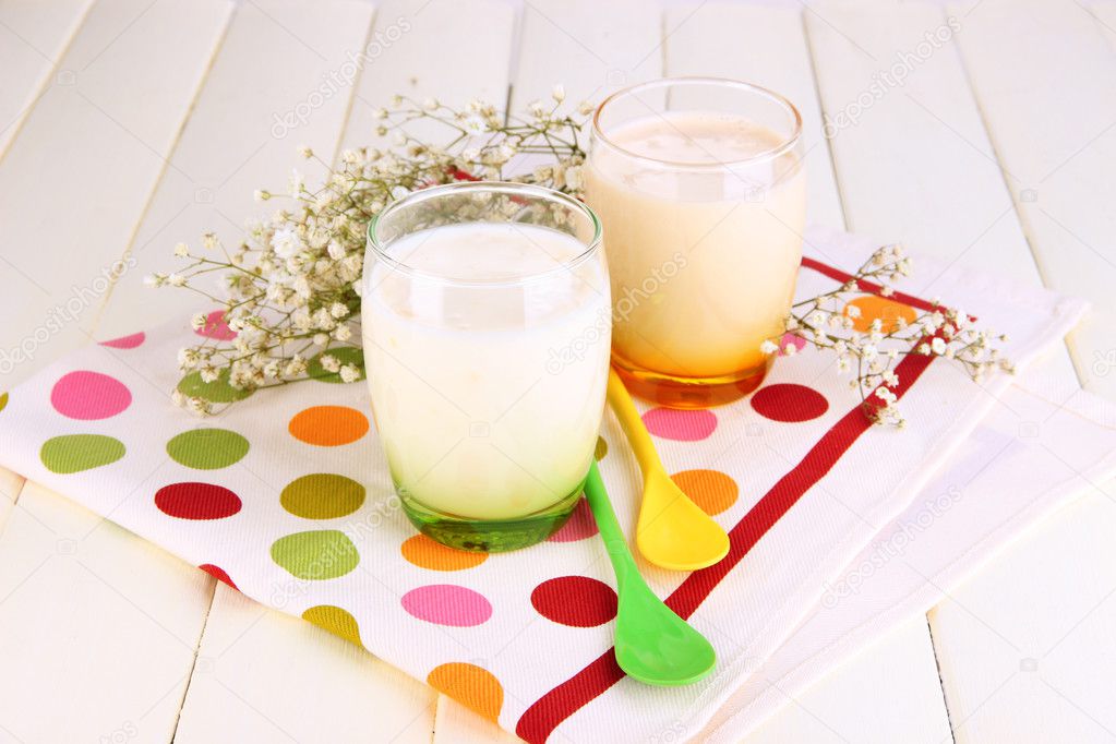 Delicious yogurts with fruits in glasses on wooden table close-up