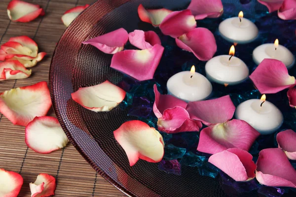 Płatki róż i świece w wody w wazonie z bliska — Zdjęcie stockowe