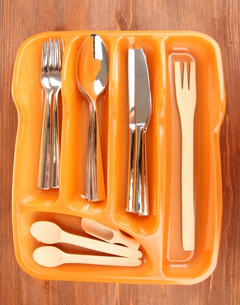 橙色塑料餐具托盘与检查的餐具和木勺子木桌子上 — 图库照片
