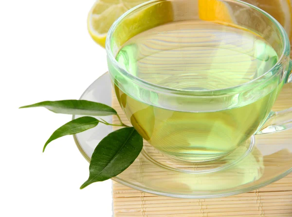 Xícara transparente de chá verde com limão no tapete de bambu, isolado em branco — Fotografia de Stock