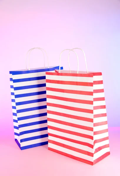 Stripped bags on light pink background — Stock Photo, Image