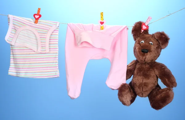 Vestiti per bambini appesi sulla clothesline, sullo sfondo di colore — Foto Stock