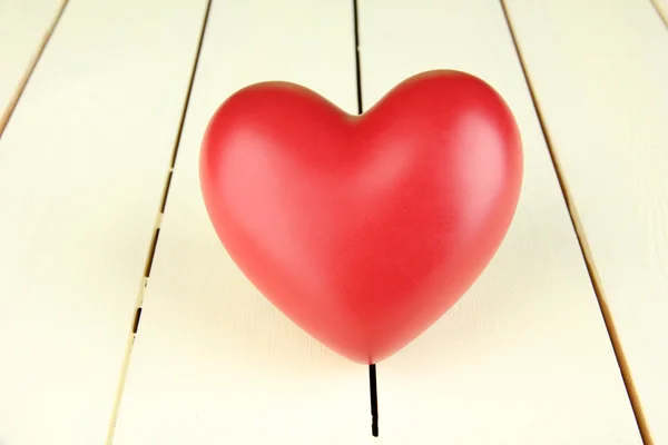 Dekoratives rotes Herz auf hölzernem Hintergrund — Stockfoto