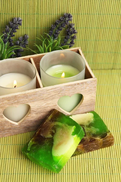 Velas en candelabro de madera, lavanda y jabón, sobre estera verde —  Fotos de Stock