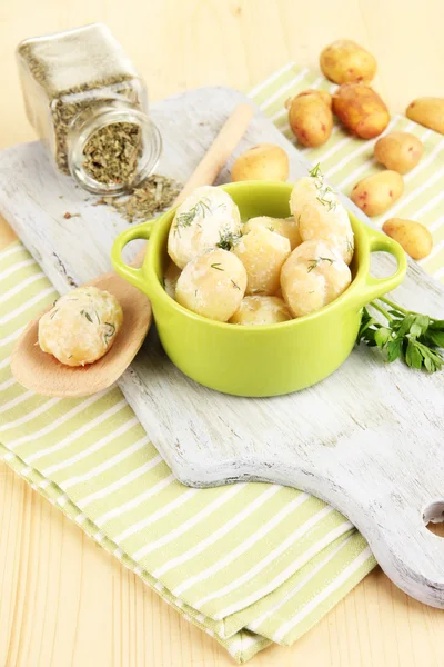 Tender young potatoes with sour cream and herbs in pan on wooden board on table close-up — Stock Photo, Image