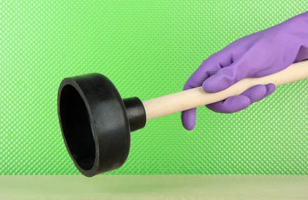 Toilet plunger in hand on green background — Stock Photo, Image